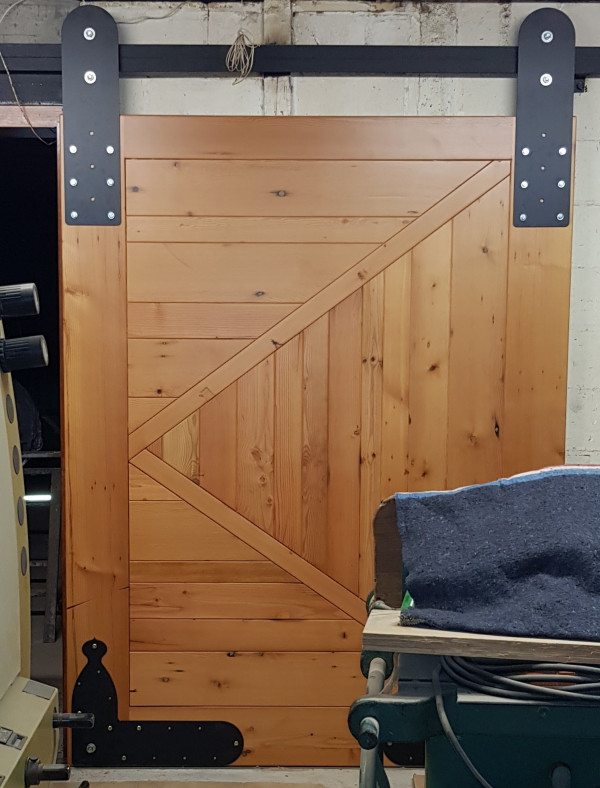 60mm Solid Oregon Pine door hanging on oversize black steel hangers on ball bearing wheels top and bottom.